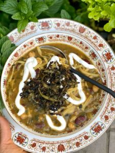 Aash Reshteh Persian Bean and Noodle Soup with Kashk or yogurt garnish and fried onion and mint topping
